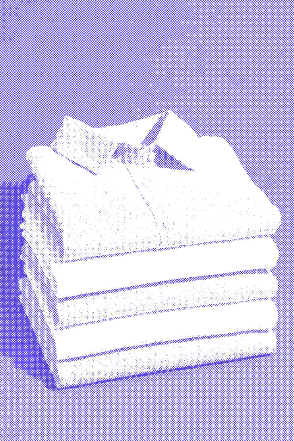 Stack of folded linen shirts in sage and oat on a blue surface